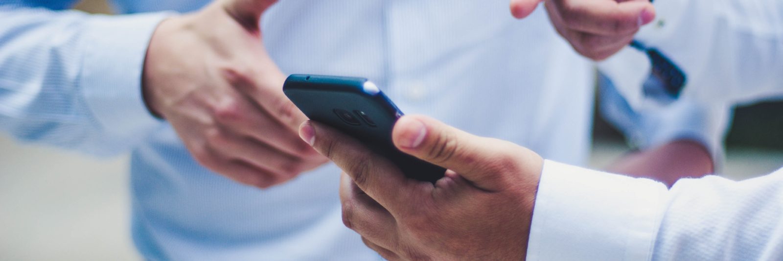 person showing smartphone to other person and pointing at it